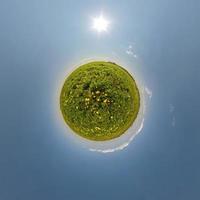 green tiny planet in blue sky with beautiful clouds. Transformation of spherical panorama 360 degrees. Spherical abstract aerial view. Curvature of space. photo