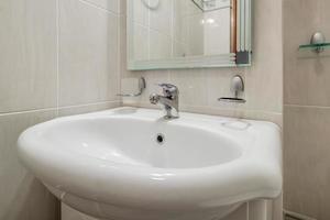 metal water tap sink with faucet in expensive bathroom. detail of a corner toilet with wall mount shower attachment photo