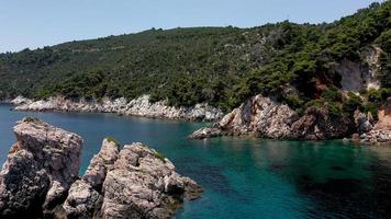 vistas aéreas de drones sobre una costa rocosa, aguas cristalinas del mar Egeo, playas turísticas y mucha vegetación en la isla de skopelos, grecia. una vista típica de muchas islas griegas similares. foto