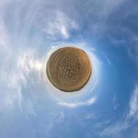 Little planet transformation of spherical panorama 360 degrees. Spherical abstract aerial view in field with clear sky and awesome beautiful clouds. Curvature of space. photo