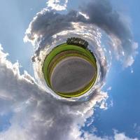tiny planet on asphalt road in blue sky with sun and beautiful clouds. Transformation of spherical panorama 360 degrees. Spherical abstract aerial view. Curvature of space. photo
