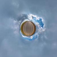 pequeño planeta en el cielo azul con hermosas nubes. transformación de panorama esférico 360 grados. vista aérea abstracta esférica. curvatura del espacio. foto