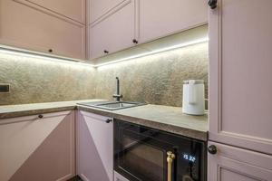 Interior of the modern luxure kitchen  in studio apartments in minimalistic style with light pink color photo