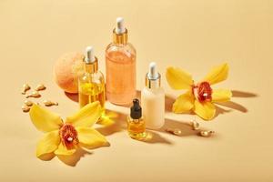 Cosmetic care products in glass bottles with orchid flowers - serums, cream, gel, oils. Concept for face and body care, wellness and spa, tropical relaxation. photo