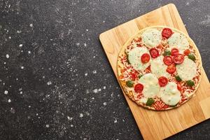 pizza congelada al horno de comida rápida con queso, tomates y pesto. listo para comer.