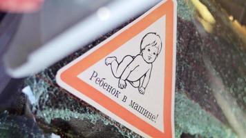 señal de advertencia de niños dentro de un camión después de un accidente con vidrios rotos. traducción niño en el coche. un primer plano de un niño en una pegatina, en la ventana trasera de un automóvil. video