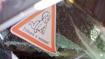 señal de advertencia de niños dentro de un camión después de un accidente con vidrios rotos. traducción niño en el coche. un primer plano de un niño en una pegatina, en la ventana trasera de un automóvil. video