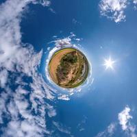 Little planet transformation of spherical panorama 360 degrees. Spherical abstract aerial view in field with clear sky and awesome beautiful clouds. Curvature of space. photo