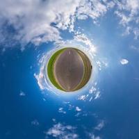 tiny planet in blue sky with sun and beautiful clouds. Transformation of spherical panorama 360 degrees. Spherical abstract aerial view. Curvature of space. photo