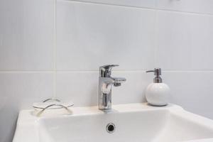 metal water tap sink with faucet with soap and shampoo dispensers in expensive bathroom photo