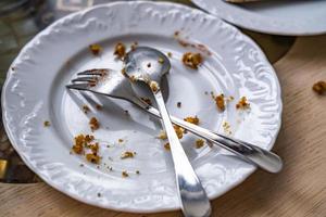 plato sucio vacío con cuchara y tenedor en la mesa después del desayuno foto
