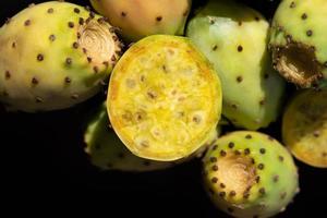 Close-up of fresh prickly pears lying against dark background. The fruits fall sideways into the picture from above. photo