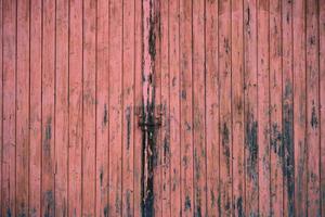 Background and texture of a weathered red wooden gate that is closed with a chain. photo