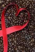 A heart is wound from a red ribbon on dried and roasted brown coffee beans photo