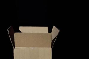 An open and empty cardboard box stands in front of a dark background photo