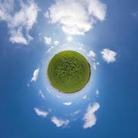 pequeño planeta verde en el cielo azul con hermosas nubes. transformación de panorama esférico 360 grados. vista aérea abstracta esférica. curvatura del espacio. foto