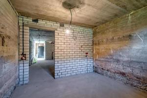 Empty unfurnished basement room with minimal preparatory repairs. interior with white brick walls photo