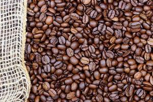 Background, close-up and texture of roasted coffee beans with a piece of jute running along the edge photo