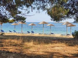 vista prístina de la bahía de una isla de Grecia con tumbonas vacías y sombrillas de playa. foto