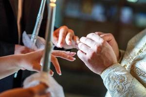 the priest helps the newlyweds exchange rings at the wedding ceremony in the church photo