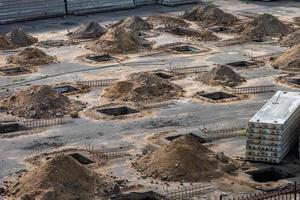 rows of pits at a construction site. preparation of the site for the installation of piles. a pile of sand photo