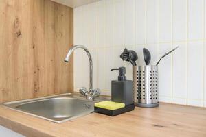 Soap and shampoo dispensers near Ceramic Water tap sink with faucet in expensive kitchen photo