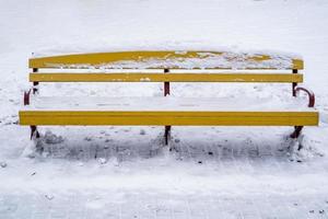 yellow wooden park benches covered with snow photo