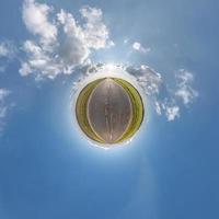 tiny planet in blue sky with sun and beautiful clouds. Transformation of spherical panorama 360 degrees. Spherical abstract aerial view. Curvature of space. photo