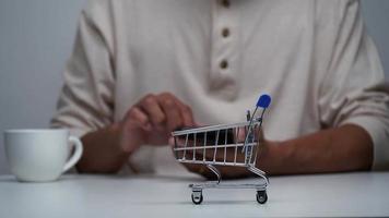 detener el movimiento de un hombre comprando en línea con un teléfono inteligente y un carrito de compras en movimiento. video