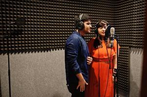 Young asian duet singers with microphone recording song in record music studio. photo