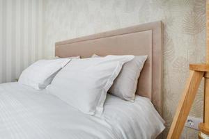 Pillows on master bed in interior of the modern luxure bedroom in studio apartments in light color style photo