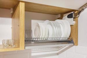 set of plates, cups on the shelf in the kitchen cabinet photo