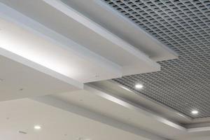 suspended and grid ceiling with halogen spots lamps and drywall construction in empty room in store or house. Stretch ceiling white and complex shape. photo