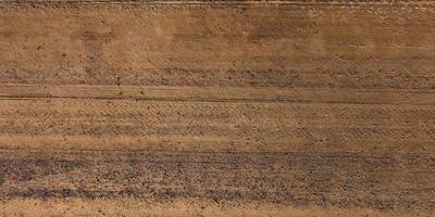 panorama of surface from above of gravel road with car tire tracks photo