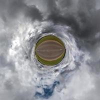 tiny planet in blue sky with beautiful clouds. Transformation of spherical panorama 360 degrees. Spherical abstract aerial view. Curvature of space. photo