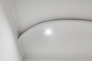 Detail of corner ceiling with intricate crown molding. Suspended ceiling and drywall construction in empty room in apartment or house. Stretch ceiling white and complex shape. photo