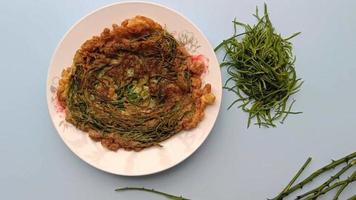 chamada tailandesa kai jeow cha om ou omelete com folhas de acácia sobre fundo azul video