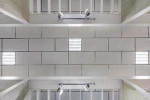 cassette suspended ceiling with square halogen spots lamps and drywall construction in empty room in apartment or house. Stretch ceiling white and complex shape. Looking up view photo