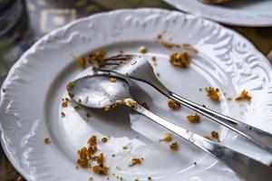 Empty dirty plate with spoon and fork on the table after breakfast photo