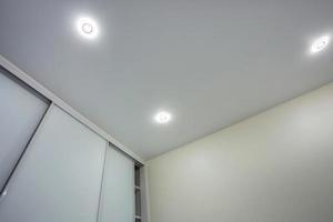 suspended ceiling with halogen spots lamps and drywall construction in empty room in apartment or house. Stretch ceiling white and complex shape. photo