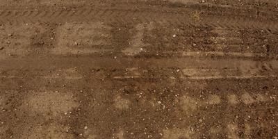 panorama of road from above on surface of gravel road with car tire tracks photo