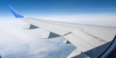 ala de avión desde la ventana del avión con vistas al cielo azul y hermosas nubes foto