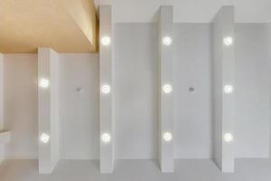 suspended ceiling with halogen spots lamps and drywall construction in empty room in apartment or house. Stretch ceiling white and complex shape. photo