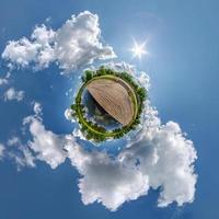 tiny planet in blue sky with beautiful clouds. Transformation of spherical panorama 360 degrees. Spherical abstract aerial view. Curvature of space. photo