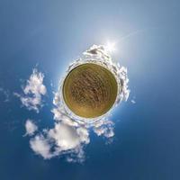 green tiny planet in blue sky with beautiful clouds. Transformation of spherical panorama 360 degrees. Spherical abstract aerial view. Curvature of space. photo