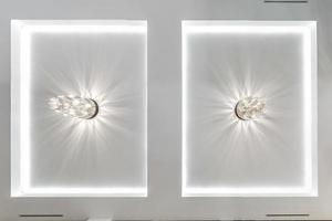 looking up on suspended ceiling with halogen spots lamps and drywall construction in empty room in apartment or house. Stretch ceiling white and complex shape. photo