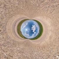 Inversion of blue little planet transformation of spherical panorama 360 degrees. Spherical abstract aerial view on road with awesome beautiful clouds. Curvature of space. photo