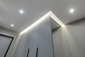 suspended ceiling with halogen spots lamps and drywall construction in empty room in apartment or house. Stretch ceiling white and complex shape. photo