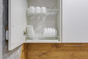 set of plates, cups on the shelf in the kitchen cabinet photo