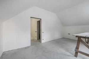 empty white room with mansard without repair and furniture with scaffolding photo